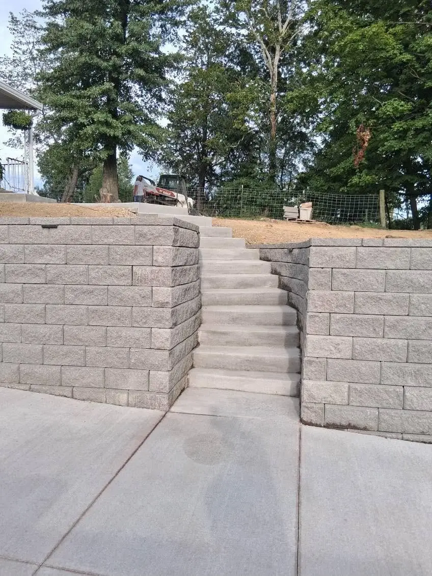 Concrete steps built into the block retaining wall in Cincinnati, OH, rising from the driveway to the upper yard