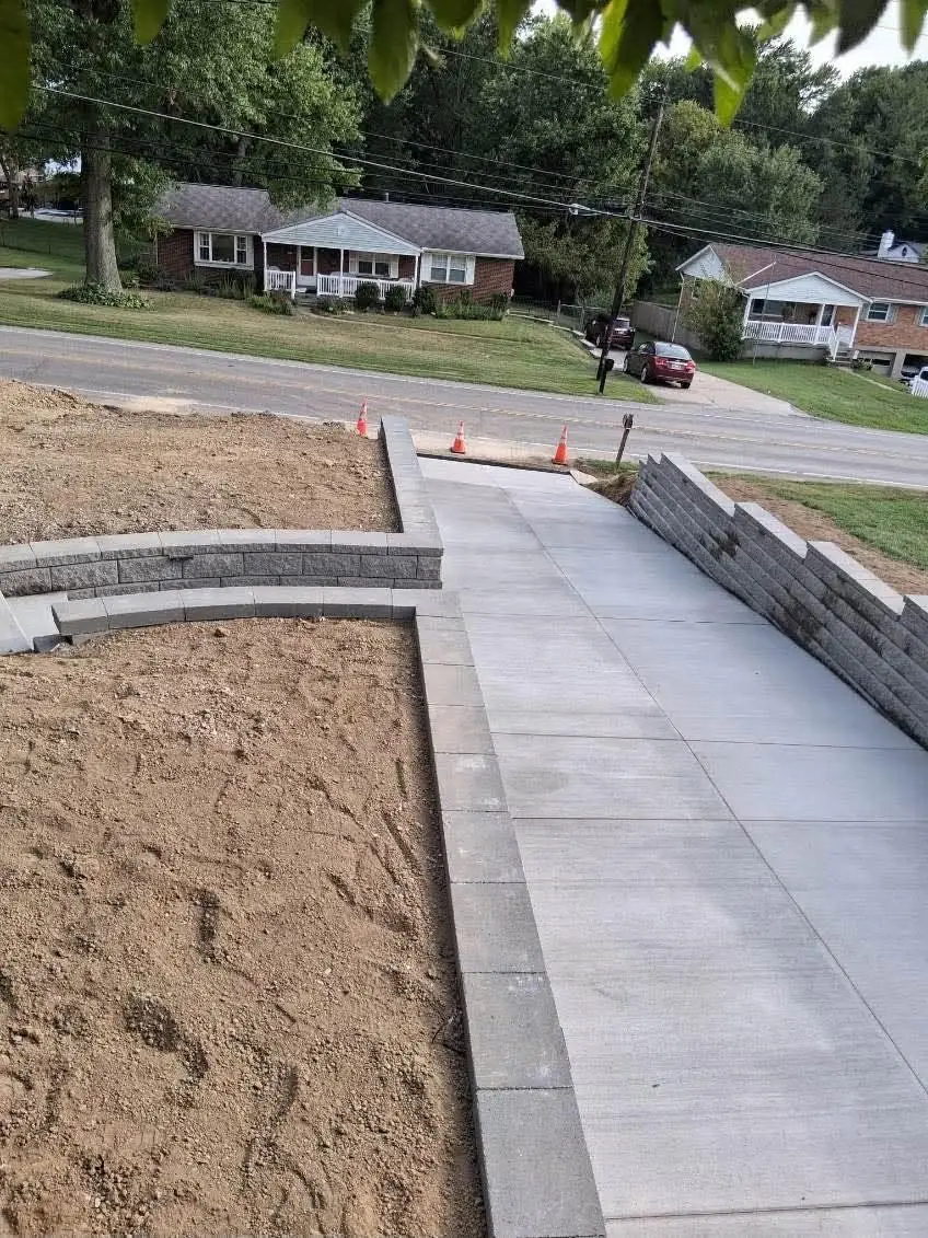 Concrete driveway and walkway in Cincinnati, OH with a curved capped block planter wall on the left