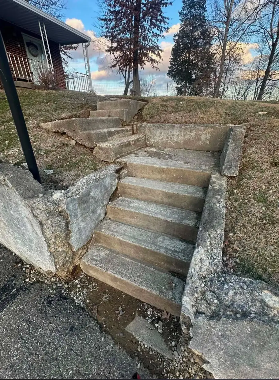 Old concrete front steps in Cincinnati, OH broken apart at the joints with the cheek walls split open