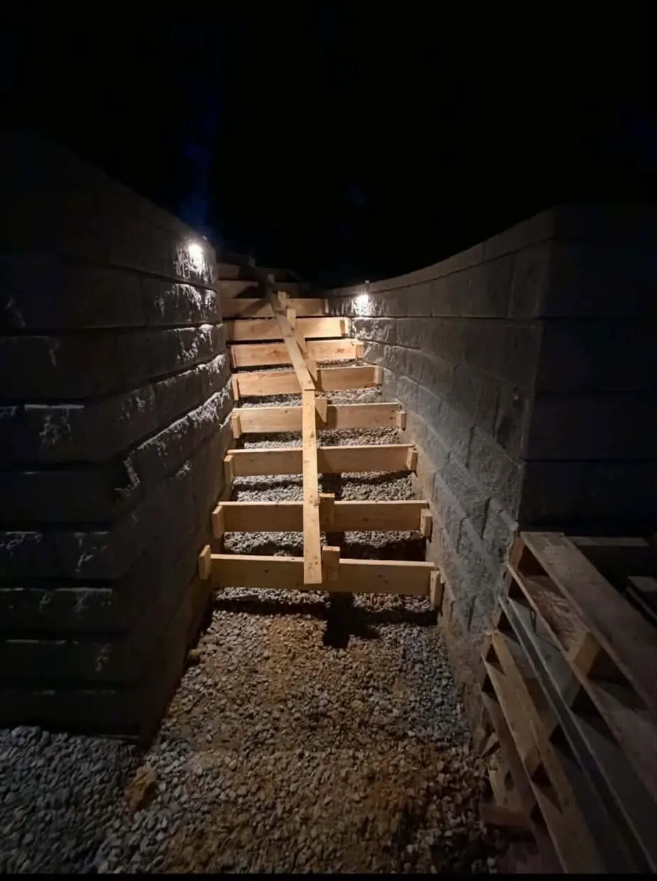Step forms set on gravel between the two lit block walls in Cincinnati, OH before the concrete pour