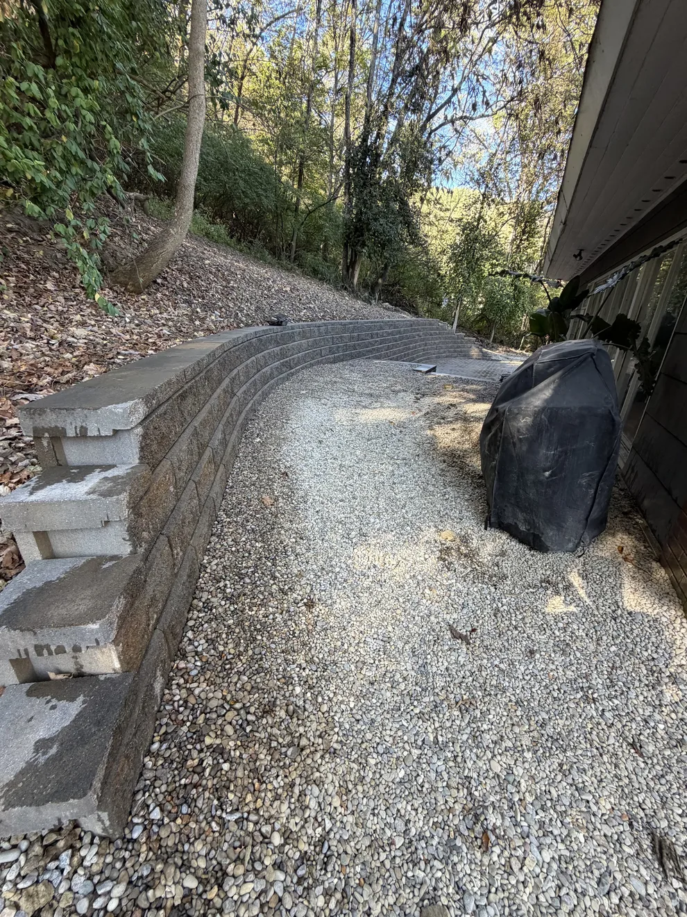 Small decorative stone bed beside the house in Cincinnati, OH, edged by the capped block retaining wall
