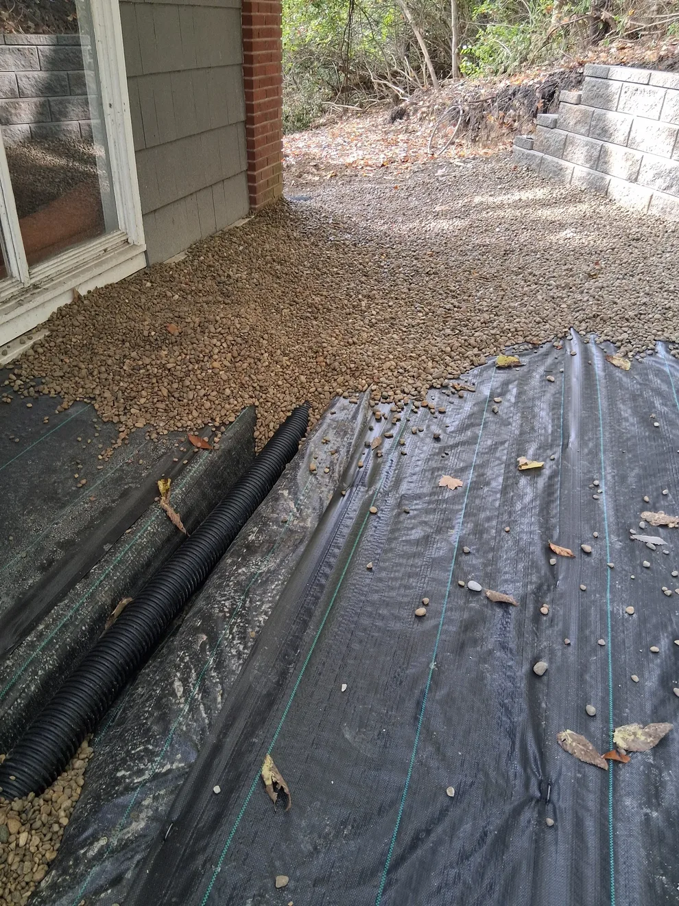 Construction fabric pinned down over the drainage pipe trench beside the house in Cincinnati, OH, with stone going on top