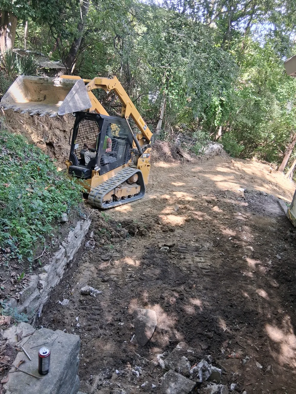 Compact track loader digging out the hillside behind the house in Cincinnati, OH