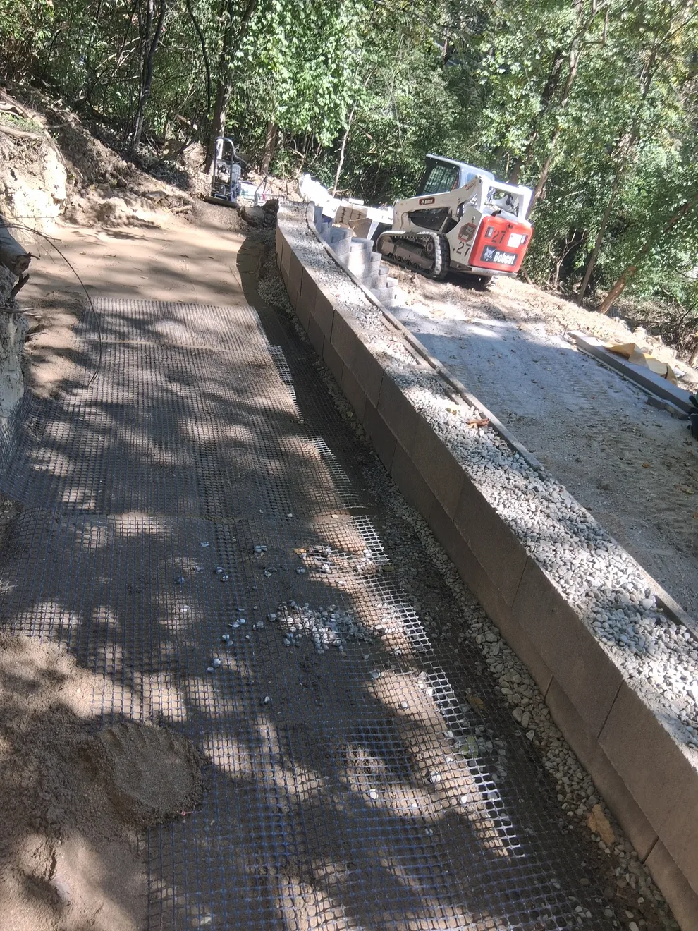 Geogrid rolled out behind the wall block with a skid steer working the far end in Cincinnati, OH