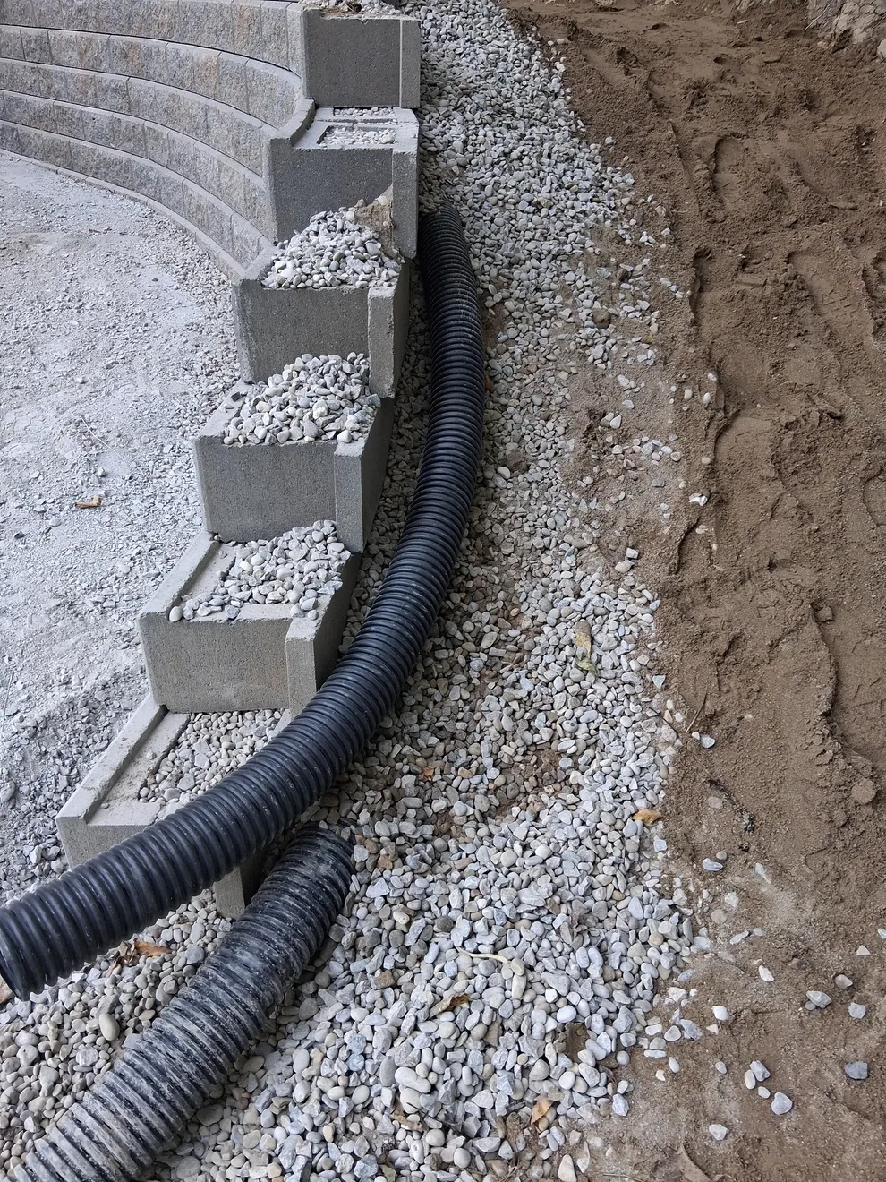 Drainage pipe behind block wall courses filled with washed stone in Cincinnati, OH