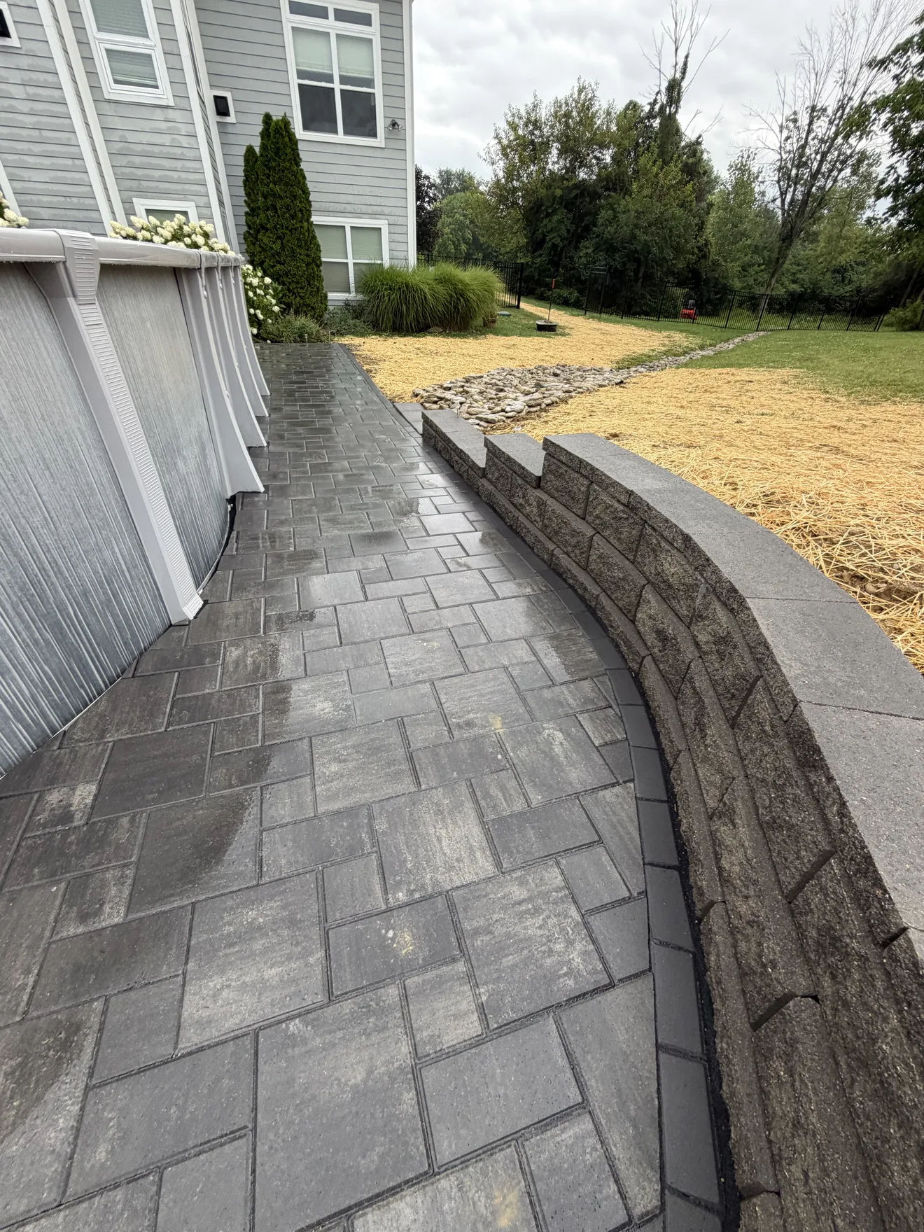 Curved gray Allen Block retaining wall with a capped top beside the new paver patio in Lebanon, OH