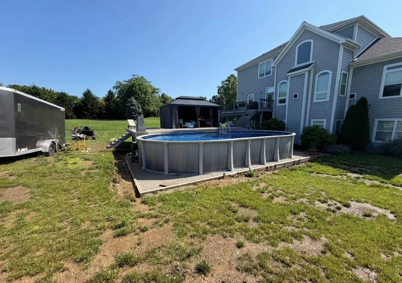 Backyard pool in Lebanon, OH before the retaining wall, sitting on bare gravel and timber edging