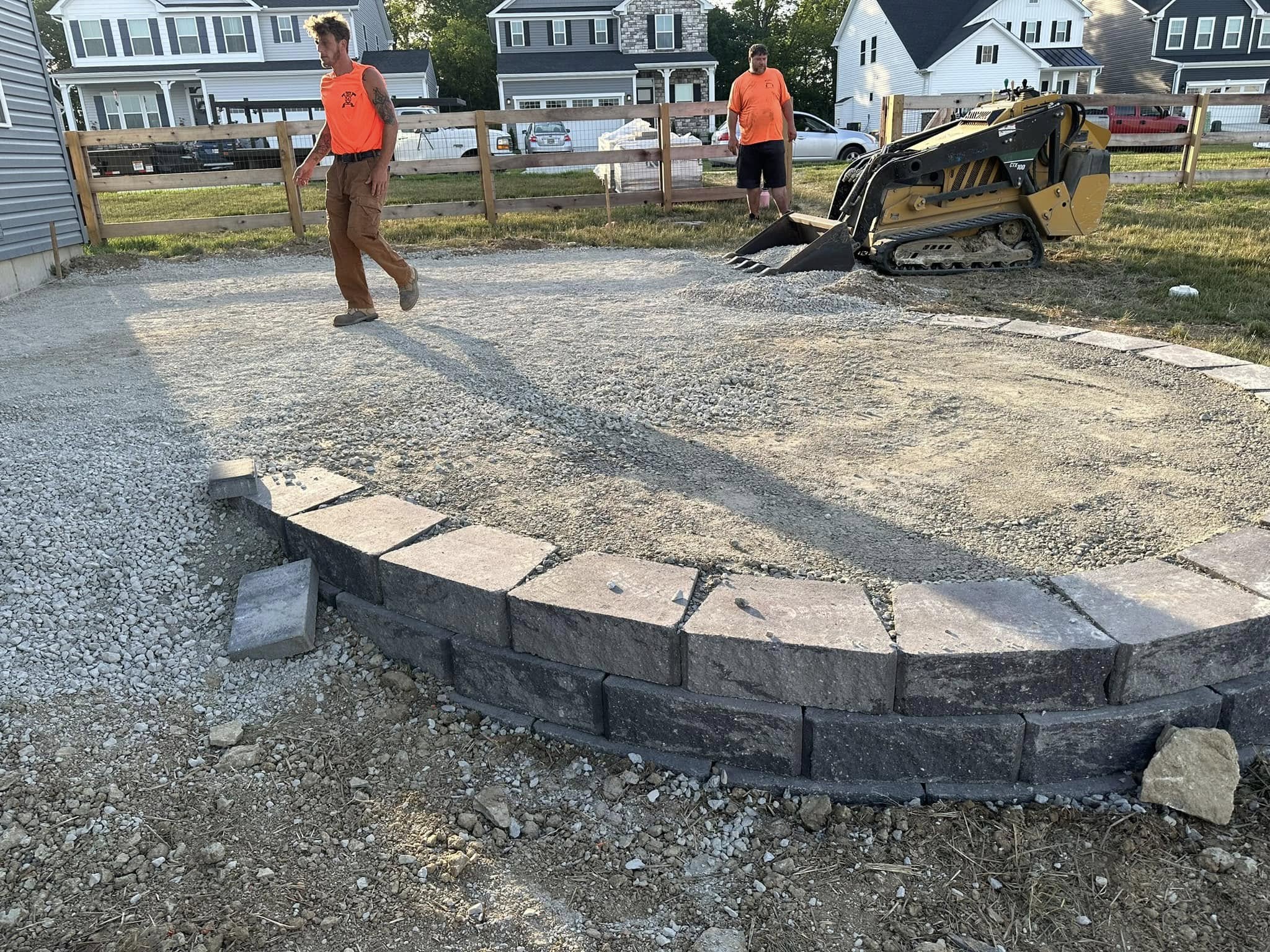 Retaining wall and paver patio base preparation in progress, with excavation and base materials installed correctly to support a durable finished project.