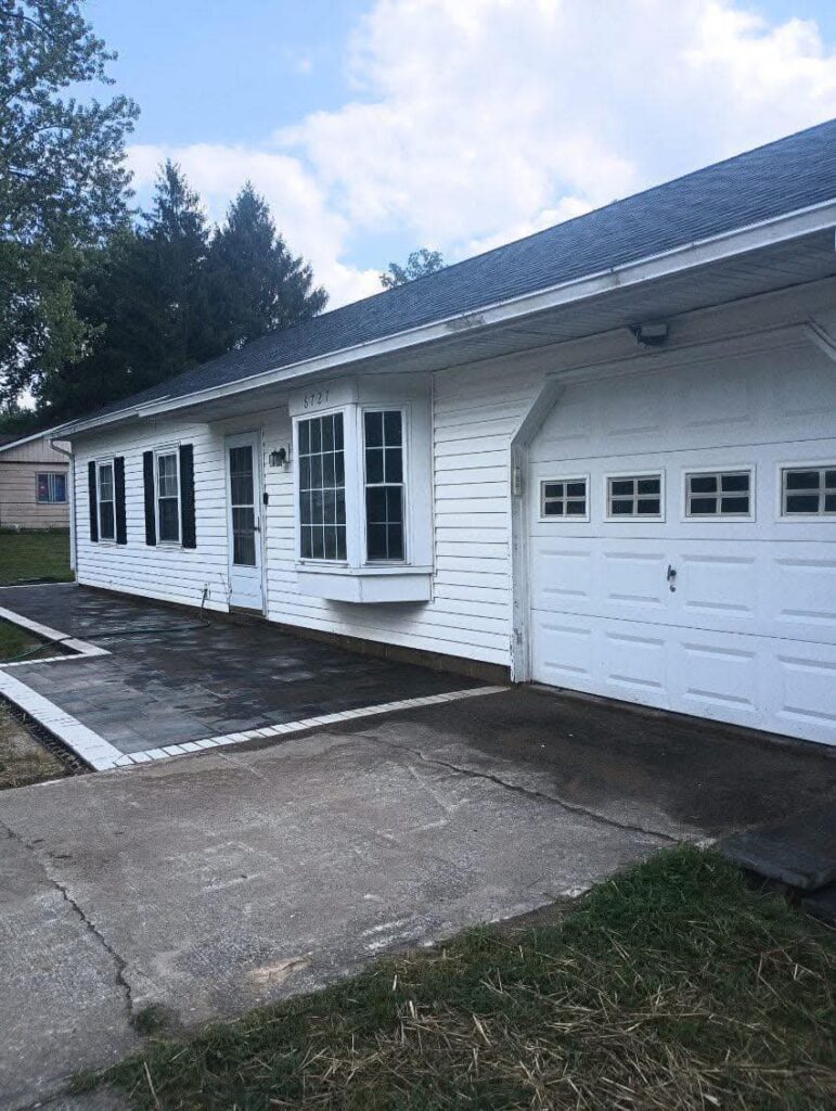 Paver patio installation with a white border accent, paired with house pressure washing for improved curb appeal, completed in Loveland, Ohio by Shawn’s Landscape & Design.