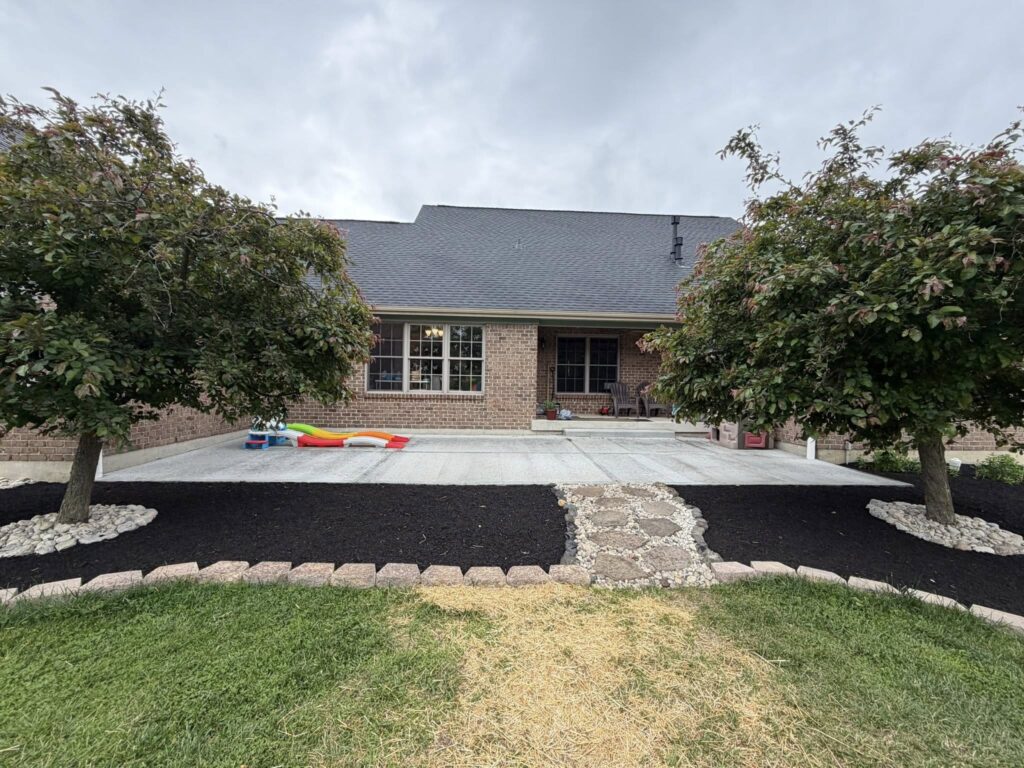 After yard drainage and grading work with finished black mulch, stone edging, cleaner landscape beds, and improved yard drainage.